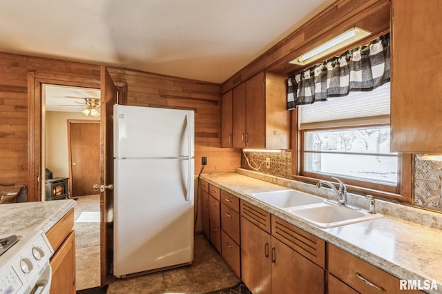 kitchen featuring sink, white appliances, and wooden walls