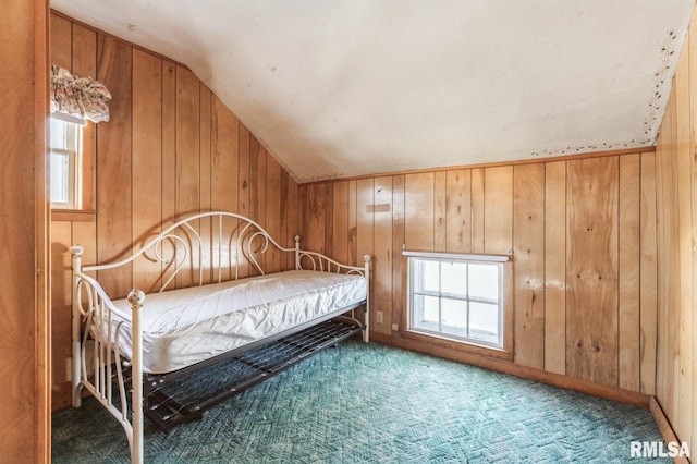 unfurnished bedroom with lofted ceiling, carpet floors, and wood walls