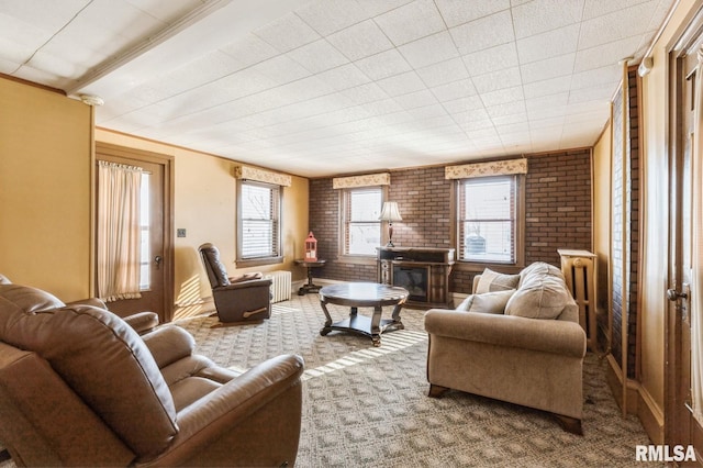 living room with brick wall, radiator heating unit, a fireplace, carpet floors, and ornamental molding