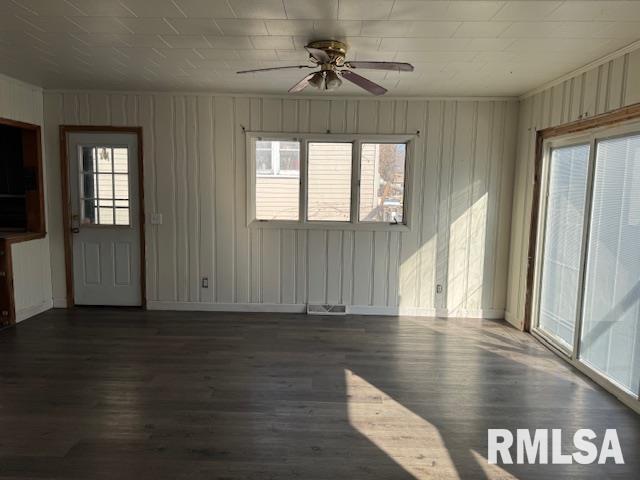1615 Iowa Ave, Clinton, IA 52732 - unfurnished living room featuring healthy amount of natural light, wood finished floors, a ceiling fan, and wooden walls