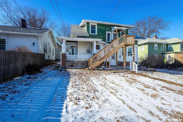 snow covered house featuring a porch