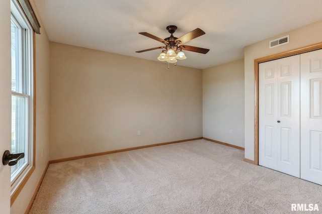 unfurnished bedroom featuring light carpet, a closet, and ceiling fan