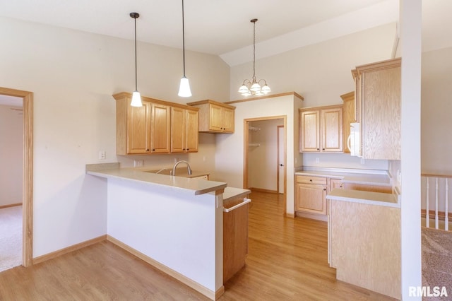 kitchen with lofted ceiling, hanging light fixtures, light hardwood / wood-style floors, kitchen peninsula, and light brown cabinets