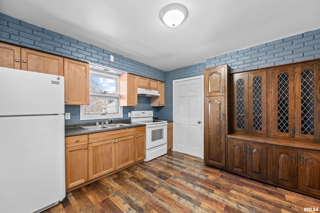 kitchen featuring dark hardwood / wood-style flooring, brick wall, sink, and white appliances