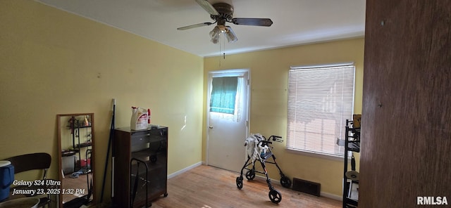 workout room with ceiling fan and light hardwood / wood-style flooring