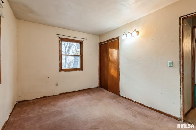 unfurnished bedroom with light colored carpet and a closet