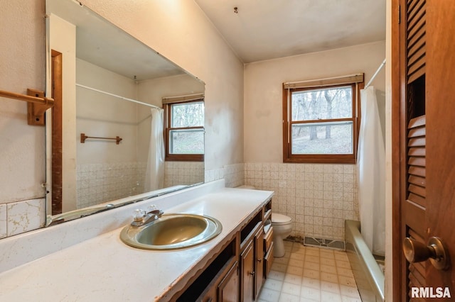 full bathroom with tile walls, vanity, a healthy amount of sunlight, and shower / bathtub combination with curtain