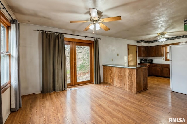 kitchen featuring white fridge, a healthy amount of sunlight, light hardwood / wood-style floors, and kitchen peninsula