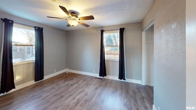 unfurnished room with ceiling fan, a textured ceiling, and light wood-type flooring