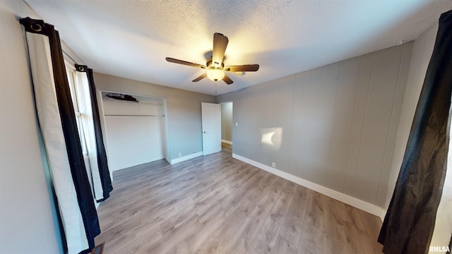 unfurnished bedroom featuring light hardwood / wood-style floors, a textured ceiling, ceiling fan, and a closet