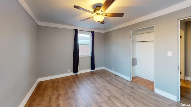 unfurnished bedroom featuring crown molding, light hardwood / wood-style flooring, a closet, and ceiling fan