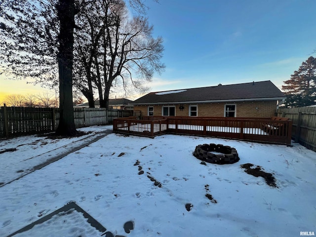 yard covered in snow with a wooden deck and a fire pit