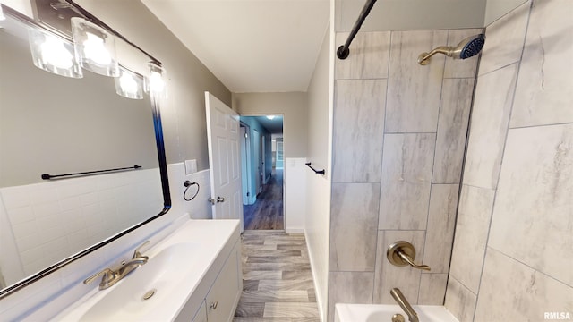 bathroom featuring vanity, tiled shower / bath combo, and tile walls