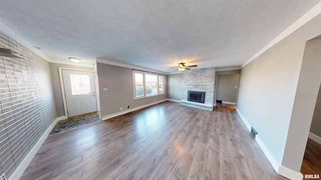 unfurnished living room featuring a stone fireplace, wood-type flooring, ceiling fan, crown molding, and a textured ceiling