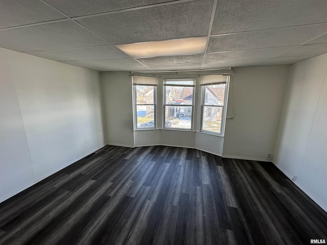 unfurnished room with dark hardwood / wood-style floors and a drop ceiling