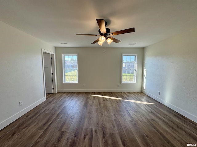 unfurnished room featuring ceiling fan, dark hardwood / wood-style floors, and a wealth of natural light