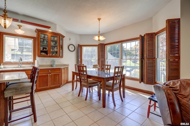 dining area with sink, a textured ceiling, and light tile patterned floors