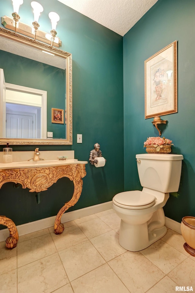 bathroom with tile patterned floors, toilet, sink, and a textured ceiling