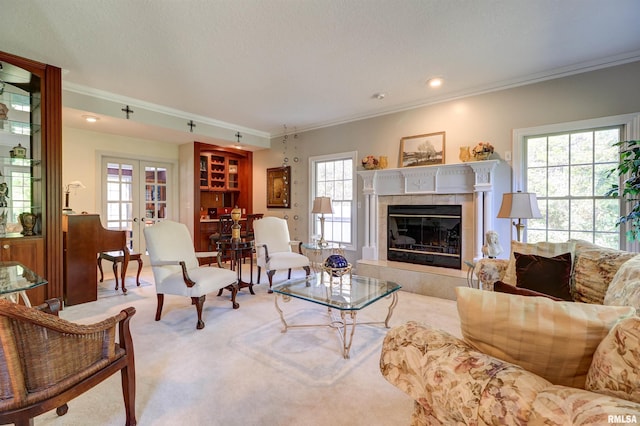 living room featuring crown molding, a tile fireplace, french doors, and a wealth of natural light