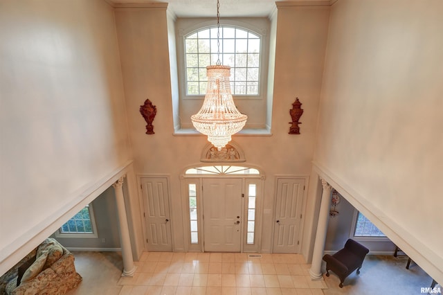 foyer featuring a notable chandelier, a towering ceiling, and light tile patterned floors