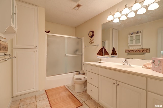 full bathroom featuring enclosed tub / shower combo, tile patterned floors, a textured ceiling, and vanity