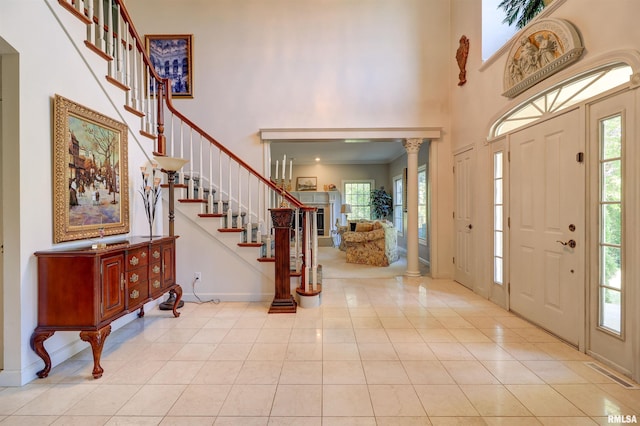 foyer entrance with decorative columns, light tile patterned flooring, and plenty of natural light