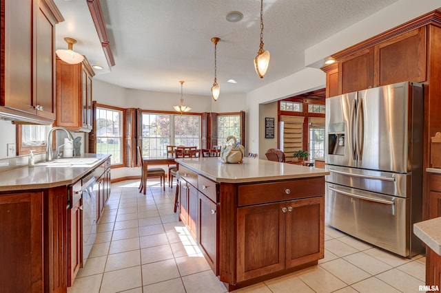 kitchen with light tile patterned flooring, sink, a center island, stainless steel fridge with ice dispenser, and pendant lighting