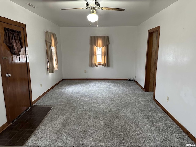 empty room featuring ceiling fan and dark colored carpet