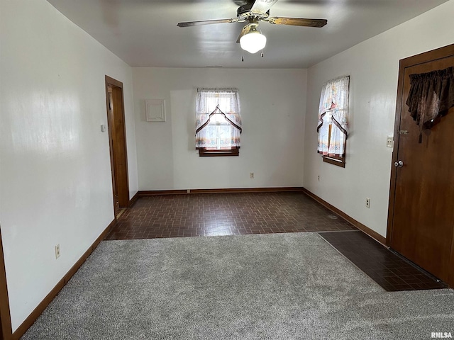 empty room with ceiling fan and dark carpet