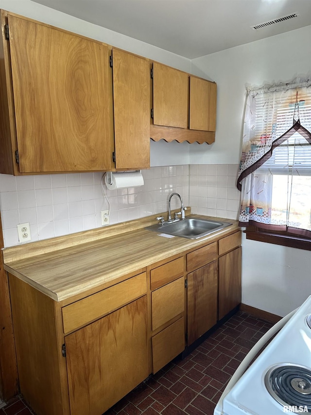 kitchen featuring electric stove, sink, and decorative backsplash