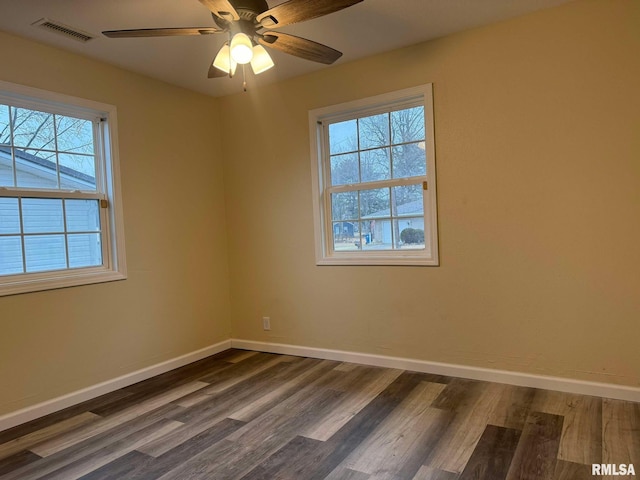 spare room featuring baseboards, visible vents, dark wood finished floors, and a ceiling fan