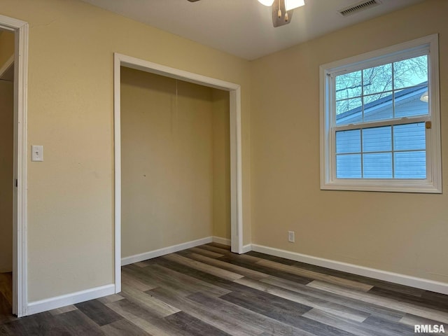 unfurnished bedroom featuring baseboards, visible vents, dark wood finished floors, and a closet