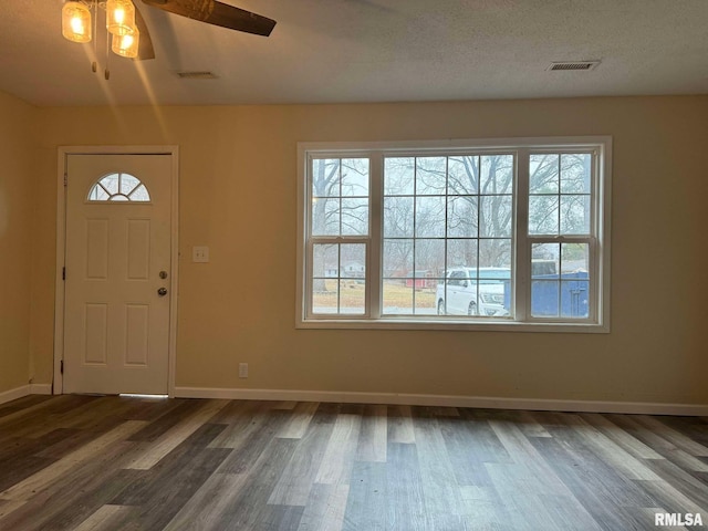 foyer featuring dark wood-style floors, baseboards, visible vents, and a textured ceiling