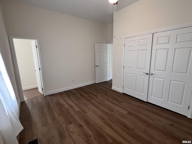 unfurnished bedroom with dark hardwood / wood-style flooring and a closet