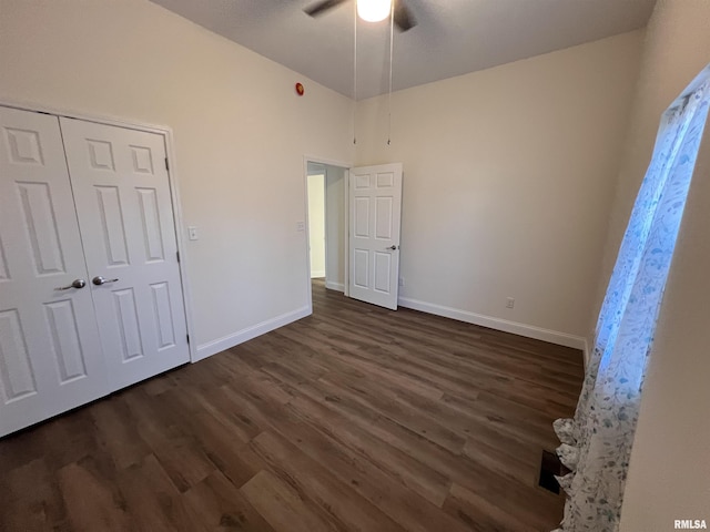 unfurnished bedroom with dark wood-type flooring, ceiling fan, high vaulted ceiling, and a closet