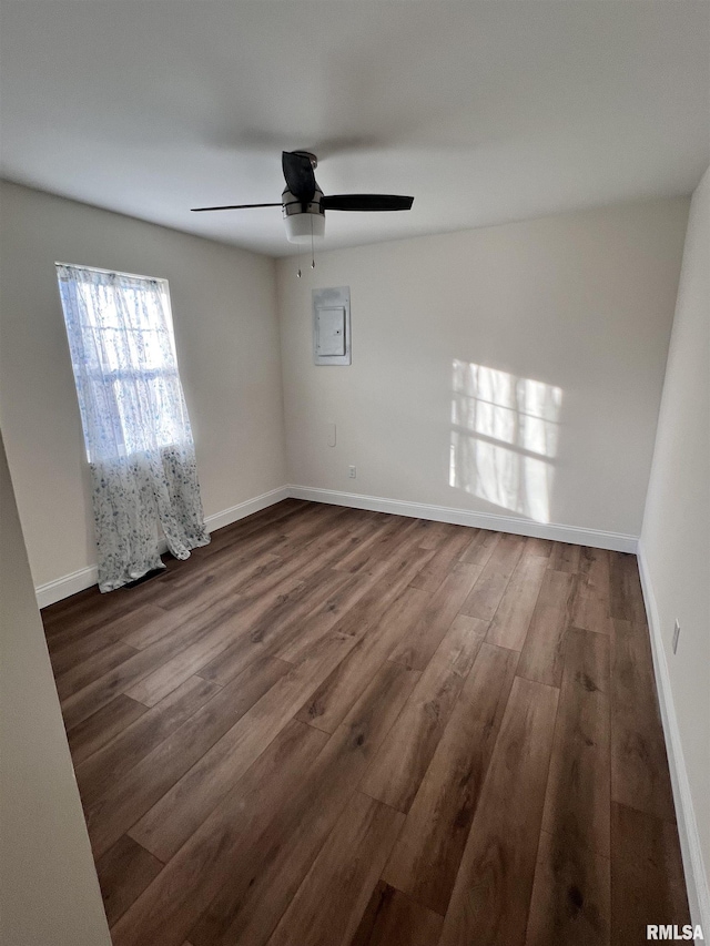 empty room with dark hardwood / wood-style flooring, electric panel, and ceiling fan