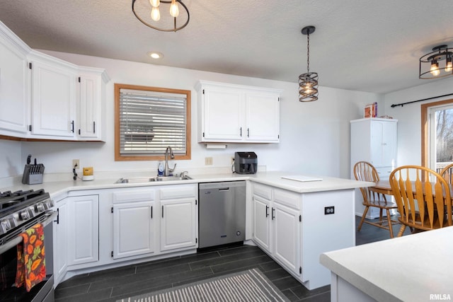 kitchen with pendant lighting, appliances with stainless steel finishes, sink, and white cabinets