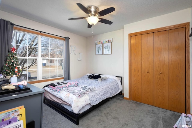 bedroom featuring ceiling fan, carpet flooring, a closet, and a textured ceiling