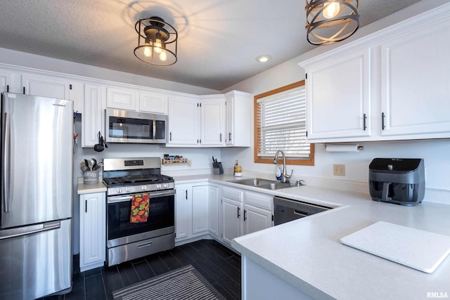 kitchen with white cabinetry, appliances with stainless steel finishes, decorative light fixtures, and sink