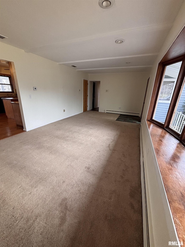 empty room featuring a baseboard heating unit and carpet floors