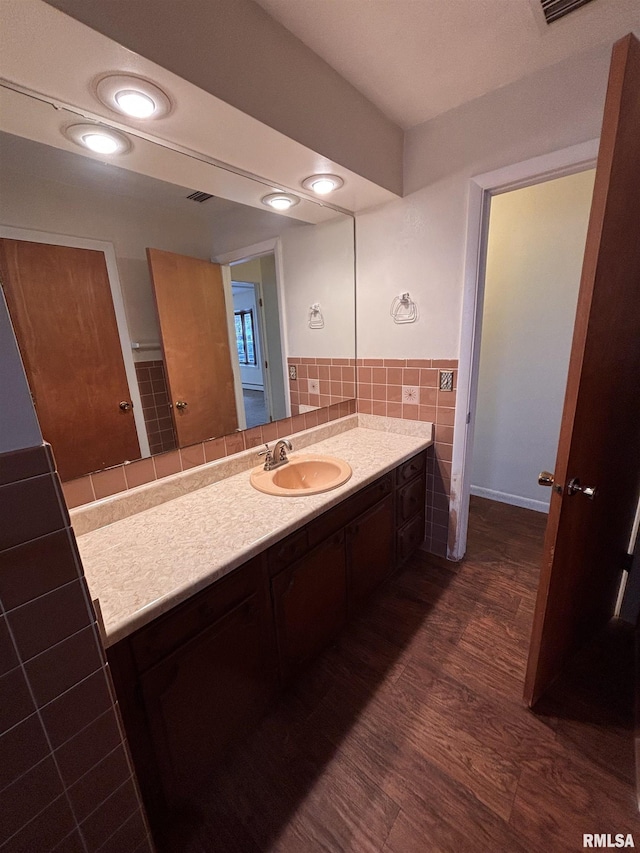 bathroom featuring vanity, hardwood / wood-style floors, and tile walls