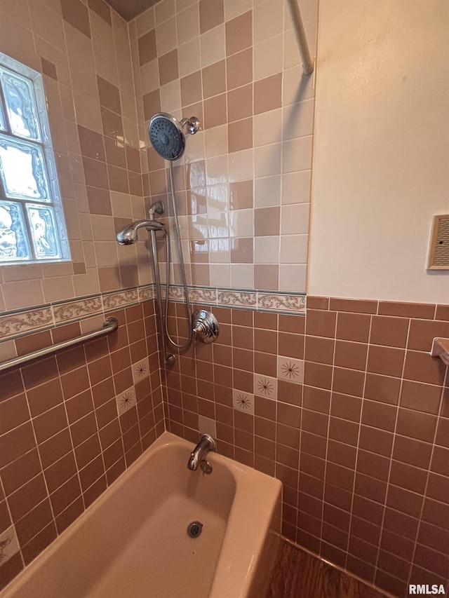 bathroom with tile walls and tiled shower / bath combo