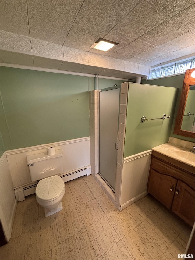 bathroom featuring a shower with door, vanity, a baseboard heating unit, and toilet