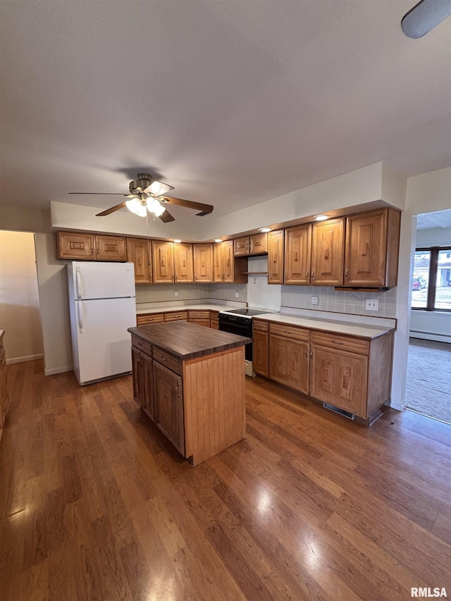 kitchen with white refrigerator, dark hardwood / wood-style floors, decorative backsplash, and electric stove