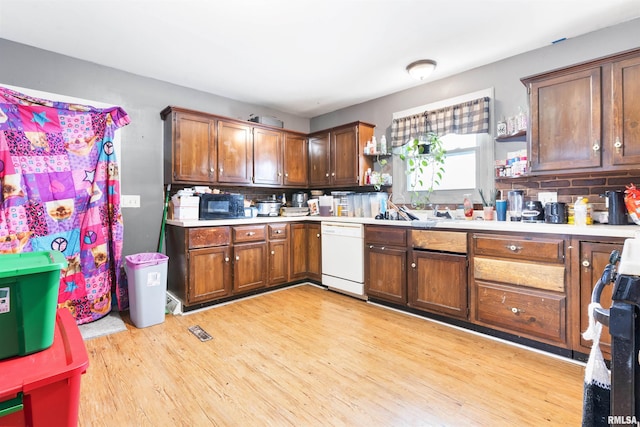 kitchen featuring white dishwasher, decorative backsplash, light hardwood / wood-style floors, and stove