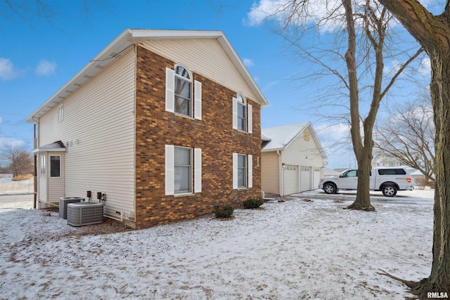 snow covered property featuring a garage and central AC