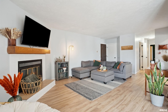 living room with a tiled fireplace and light wood-type flooring