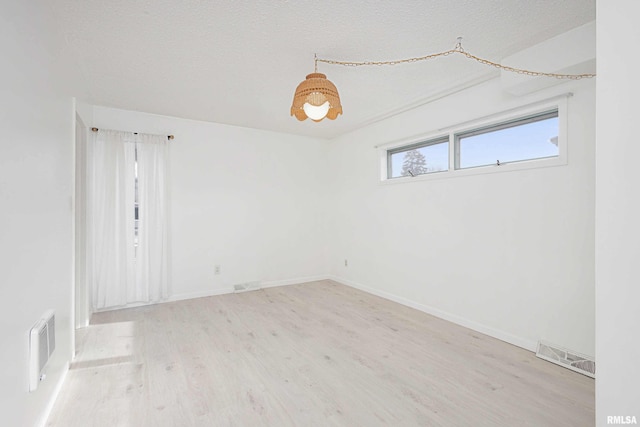 spare room featuring light hardwood / wood-style flooring and a textured ceiling