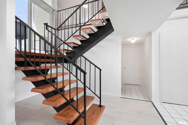 stairway with tile patterned flooring and a textured ceiling