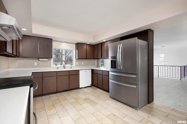 kitchen featuring appliances with stainless steel finishes, dark brown cabinets, exhaust hood, and backsplash